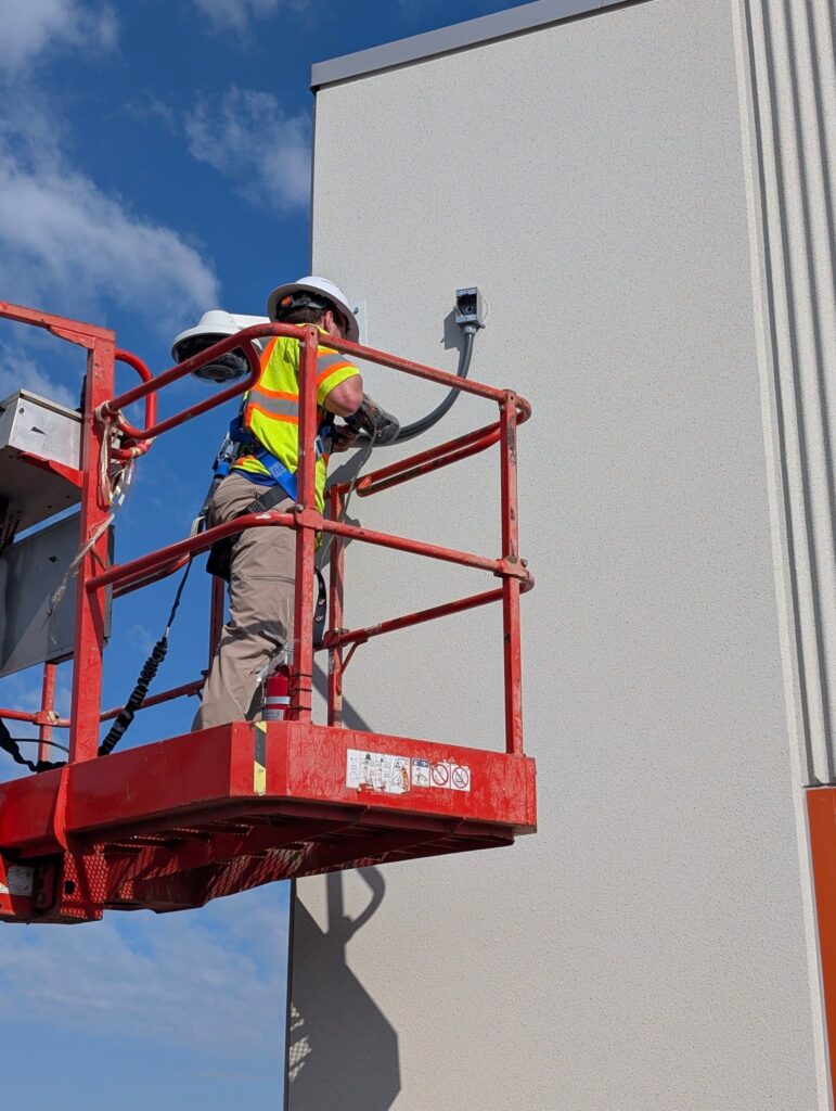 Commercial Surveillance technican on ladder Technician on a ladder installing security cameras on a commercial building